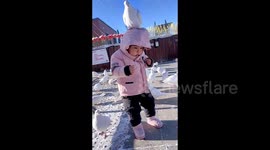 Scared baby freezes as pigeon lands on head in China