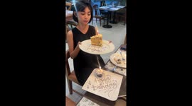 Woman blows out birthday cake candle which amusing reignites