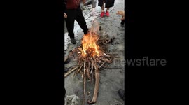 Drivers stranded on closed highway due to heavy snow salvage wood for fireside warmth