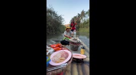 Extreme BBQ! Friends have picnic lunch on bamboo river raft