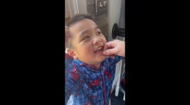 Wobbly farewell: Little boy grins as his first tooth takes flight