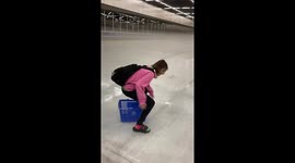 Girl slides across ice skating rink on basket
