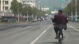 Man carries a child while riding