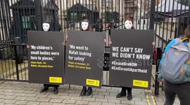 Amnesty activists dressed in black and donning masks stage a silent protest for Rafah in Gaza outside Downing St