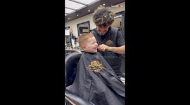 Adorable kid can't stop laughing while getting his hair trimmed