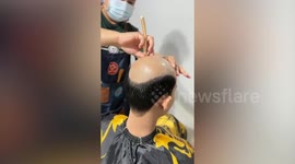 Barber glues realistic wig on bald man's head