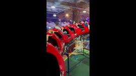 Kids and parents ride caterpillar roller coaster going around Leaning Tower of Pisa replica