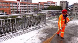 A worker cleans frozen snow from a pedestrian bridge in Yichang, China