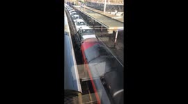 Really long train carrying cars go through Bedford station