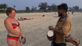 Indian beach hawker speaks fluent Russian tries to sell drums to Russian lady on Cavelossim beach in Indian state of Goa