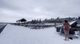 A daredevil young man does a flip into icy waters in Washington State, off a snow covered pier, in a daring polar plunge (cold plunge in the Pacific)