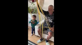 Grandfather teaches toddler how to make ball from coconut leaves