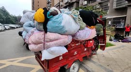 Man buys used clothes in front of a commercial residential building in Enshi, China