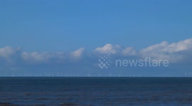 Walney Wind Farm viewed from Cleveleys, Lancashire, UK. It's a bright, sunny but cold day, with the sound of the sea breeze and waves washing onto the shore. Video taken Sunday 3rd March, 2024.