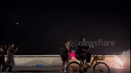 Firework flies and tucks behind man's jacket during celebration in China