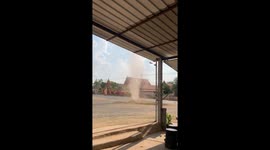 Mini dust devil tornado dances playfully across car park