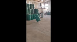 Porter rolls slightly tilted oil drums to arrange them at warehouse