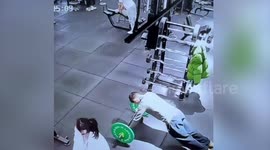 Bizarre moment woman lifts stranger's legs at gym and rolls him away as he holds onto barbell