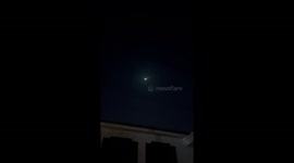 Shooting star streaks across night sky above Bangkok