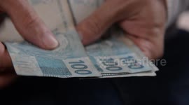 Close-up of a person's hands counting money from money laundering and washed notes hanging on the clothesline.
