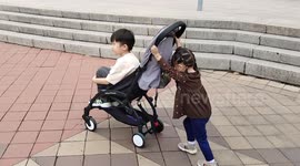 Adorable 2 years old Little Girl Pushing 6 Years Old Brother who Sitting on Stroller