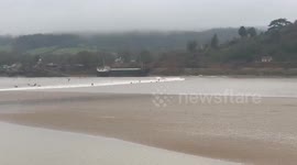 UK: Surfers Ride Severn Bore In Severn Estuary