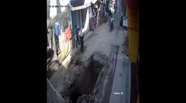 Dramatic footage shows a biker fell into an open pit in the middle of the road , locals runs to rescue