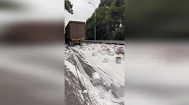 Hundreds of barrels of paint spill onto road when lorry overturns