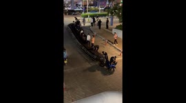 Passersby help struggling worker pick up row of trolleys that toppled over