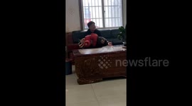 Child lying in her father's arms and playfully squirming around in Guizhou, China