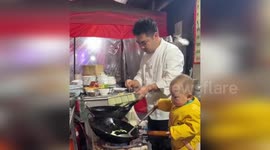 One-year-old 'Chef' helps dad prepare stir-fried rice behind food stall