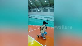 Student launches plastic toy plane propelled by rubber band in school gym