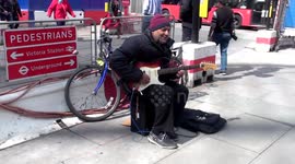 Street musician plays a cheerful melody on guitar at Victoria Station - London