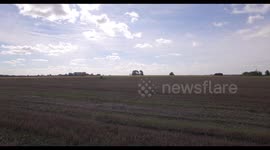 Aerial shot across fields and trees, some factory buildings