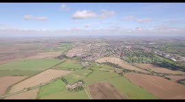 Aerial shot of factory buildings, warehouses surrounded by fields