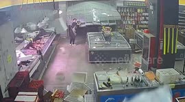 Employee struggles to close grocery store's shutters as powerful wind blows it open