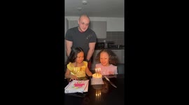 Sisterly teamwork: birthday girl gets help blowing out candles