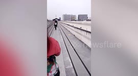 Passengers walk along railway after metal parts dislodge from train tracks in Bangkok
