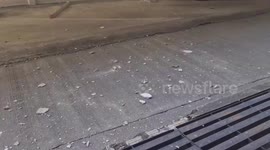 Car reverses through parking barrier and hangs precariously over the edge