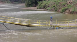 Locals risk lives by crossing bridge damaged by flooding in Indonesia