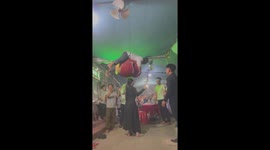 The woman uses her head to lift a giant drum with the man