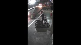 Monkey steals bag of food from motorcycle parked outside shop