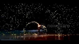 Beach goer juggling fire, slow motion fire spinning on beach in Thailand