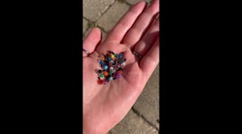 A close up of a hand filled with very tiny realistic nail polish bottles. They are all hand sculpted and painted by the artist.