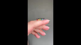 A row of tiny nail polish bottles posed in rainbow order on my finger