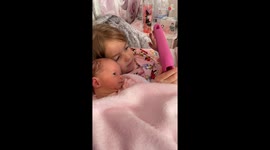 Adorable newborn trying to fight sleep while bonding with her loving big sister