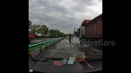 Trucker steps onto waterlogged motorway to catch fish from deluge in China