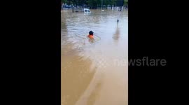 Man navigates neck-deep floodwaters with waterproof scooter in southern China