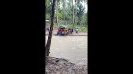 Locals rally: carrying a vehicle across flooded river after bridge collapse