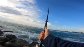Fisherman holds onto giant catch despite being battered by huge waves
